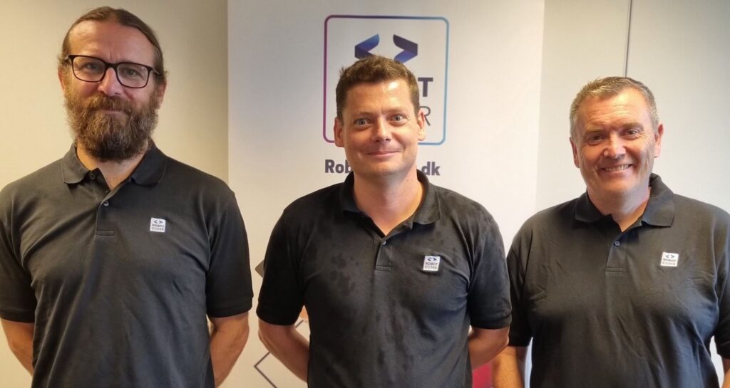 Rasmus Hansen, René Klaris og Claus Juel Nielsen foran RobotCoder-banner i forbindelse med udvidelse af teamet