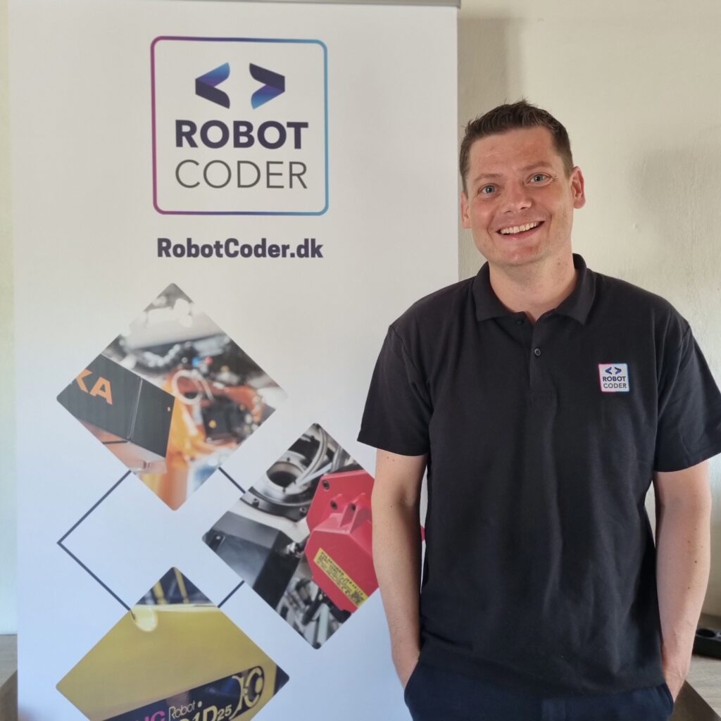 René Klaris foran RobotCoder-banner i forbindelse med godkendelse som uvildig rådgiver under SMV:Digital